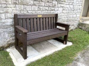 The stone wall sets off the traditional Dale bench in Brown at Tideswell in Derbyshire witha brass plaque